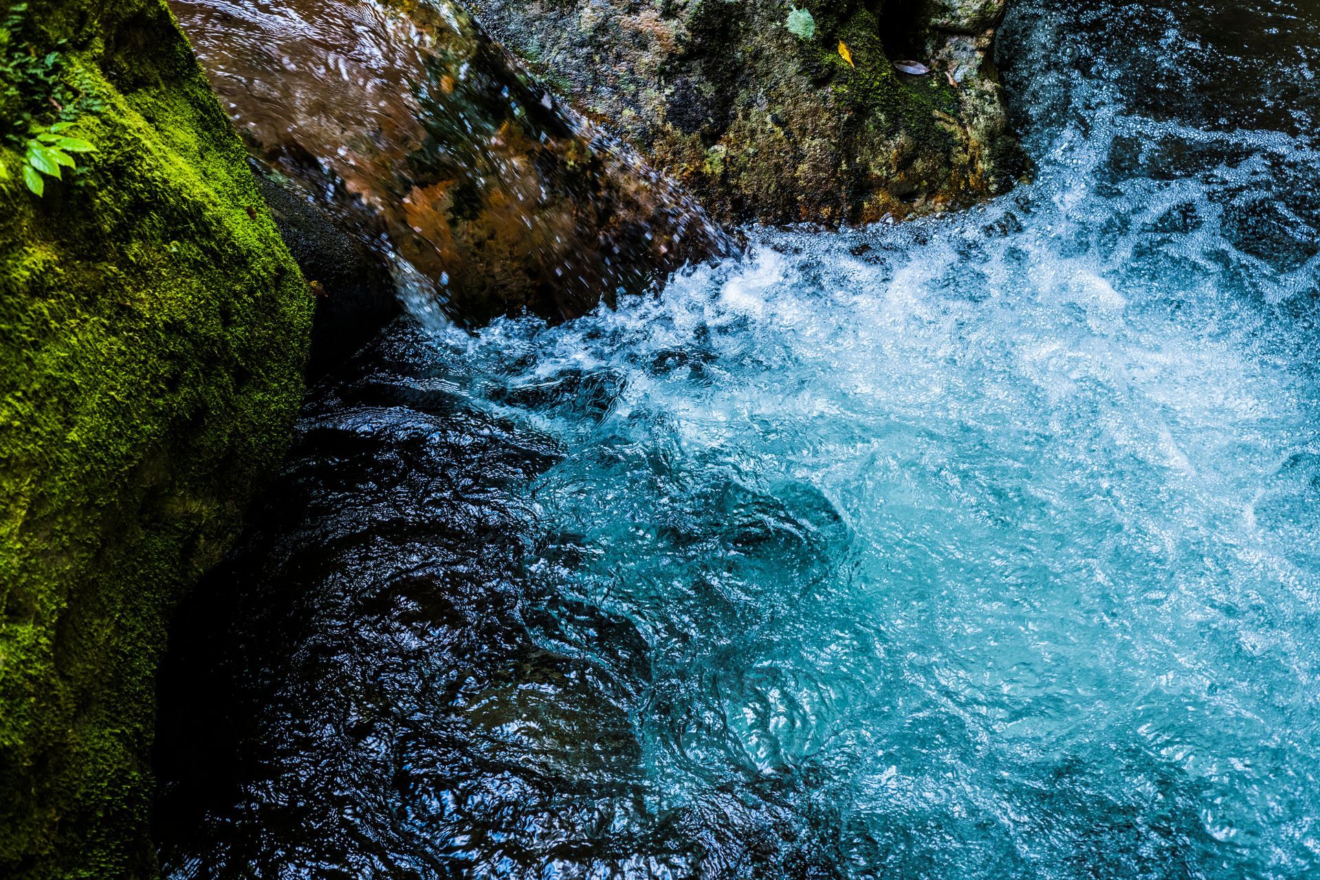 Rushing turquoise water cascades over mossy rocks. Rushing turquoise water cascades over mossy rocks.