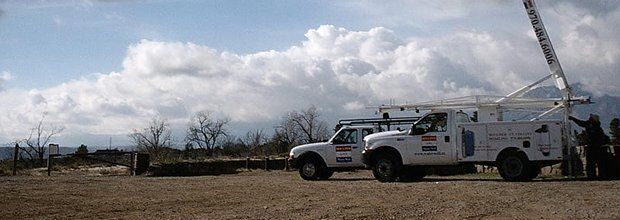 A white truck with a crane on the back is parked in a field. A white truck with a crane on the back is parked in a field.