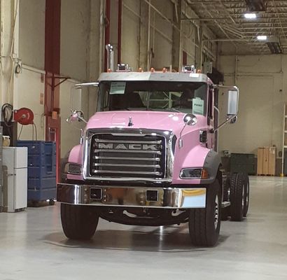 A pink mack truck is parked in a warehouse