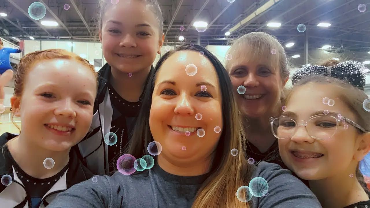 Five people smiling for a selfie indoors, with bubble effects over the photo.