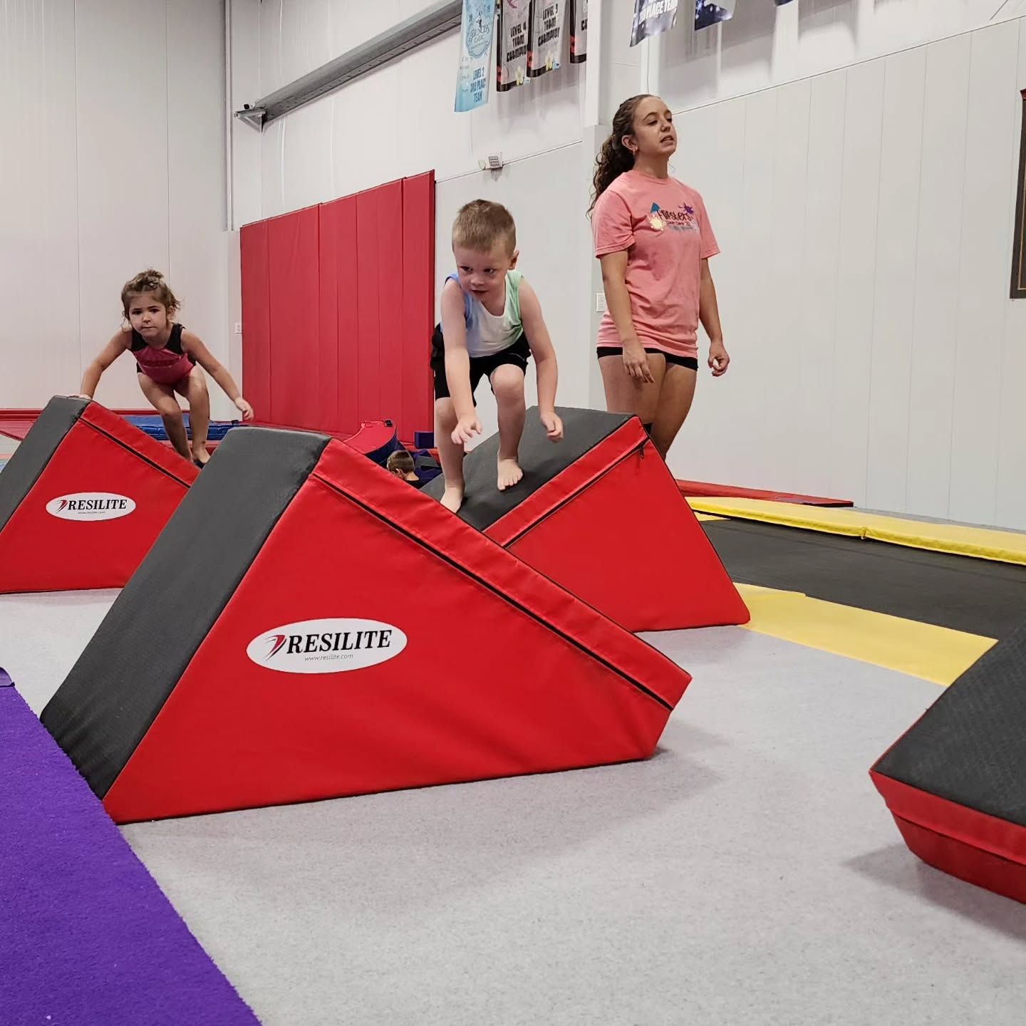 Children climbing red foam gym blocks in a bright indoor play room