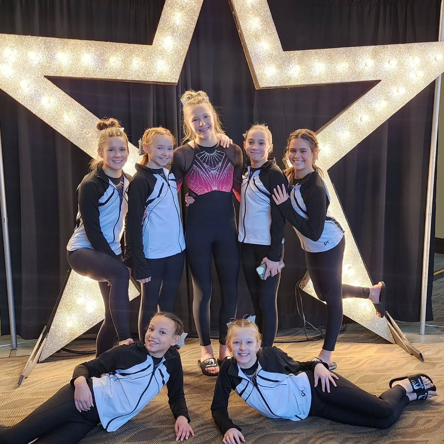 Cheer team posing in front of lit star decorations on a stage