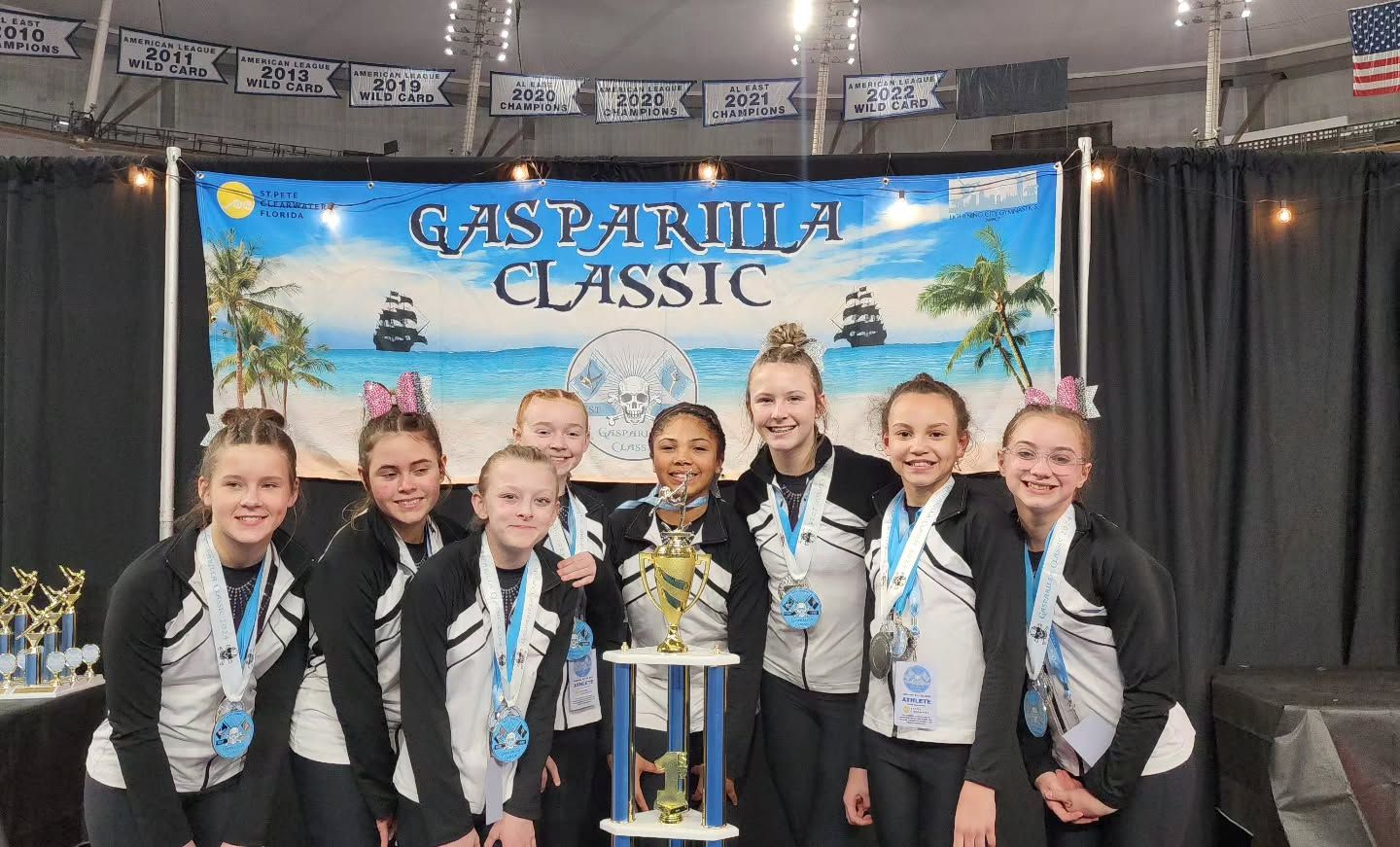 Eight cheerleaders holding a trophy in front of a “Caspatria Classic” banner