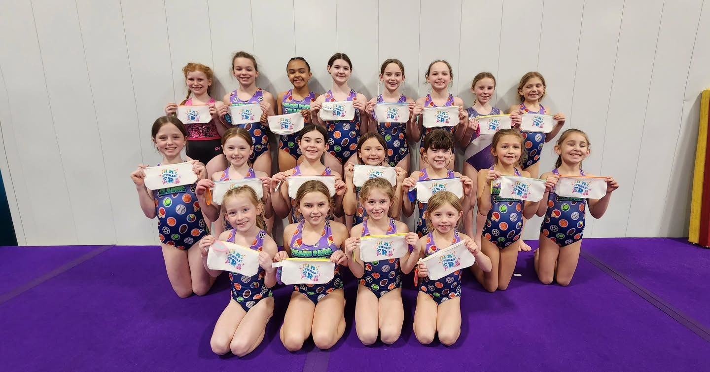 Group of young dancers posing in matching costumes on a purple mat indoors