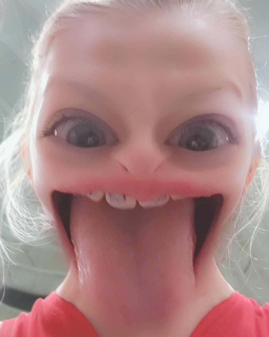 Close-up of a person with a playful face filter, wide eyes, and tongue sticking out