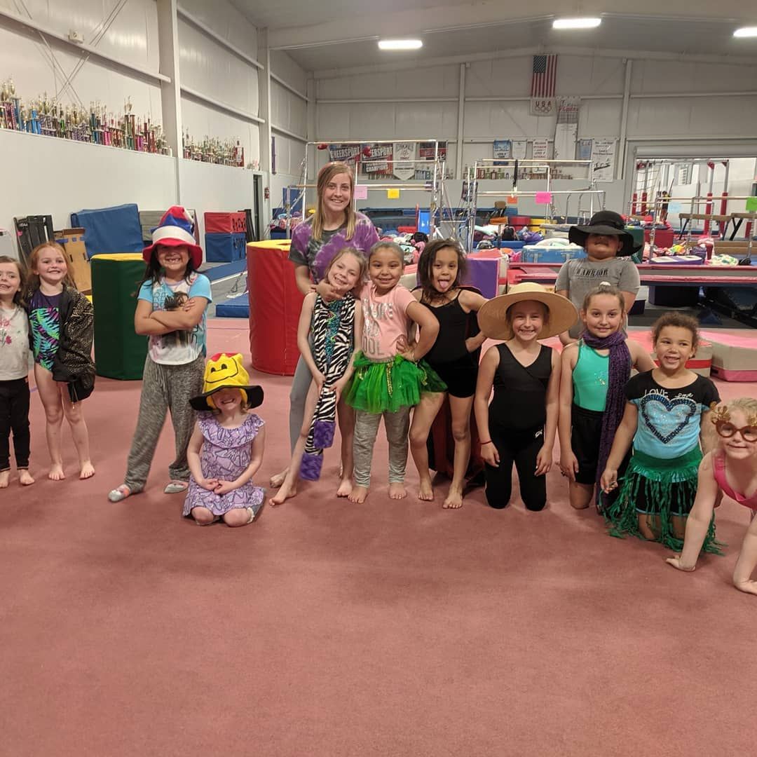 Children in colorful costumes posing in a gym or studio with pink floor mats