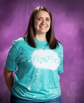 Smiling person in a turquoise tie-dye T-shirt against a purple background.