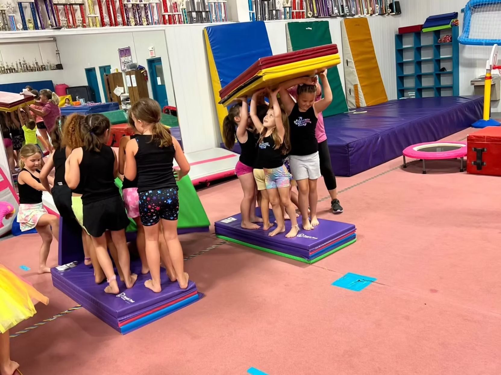 Children stacking colorful mats in a gym class room