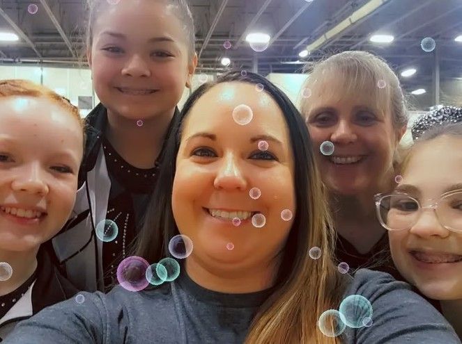 Group selfie of five smiling people indoors with a bubble filter applied