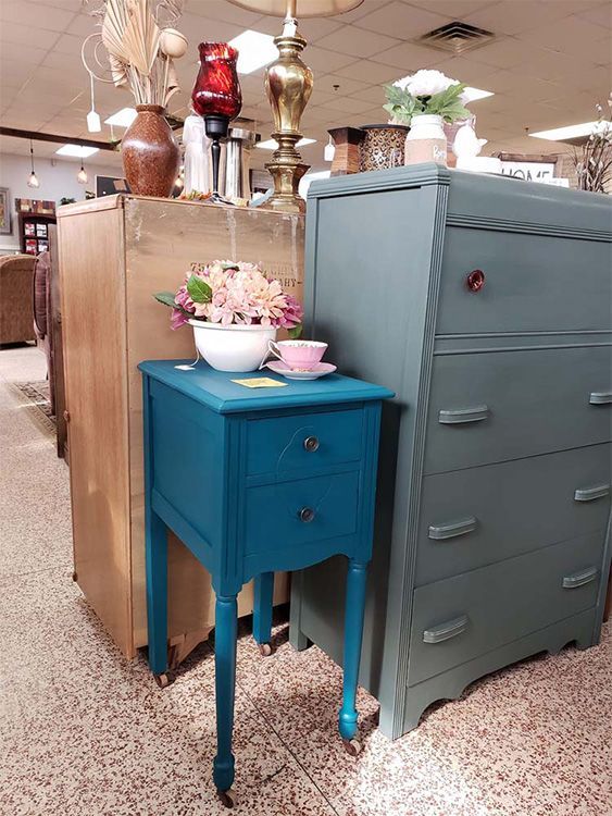A blue table with a bowl of flowers on top of it