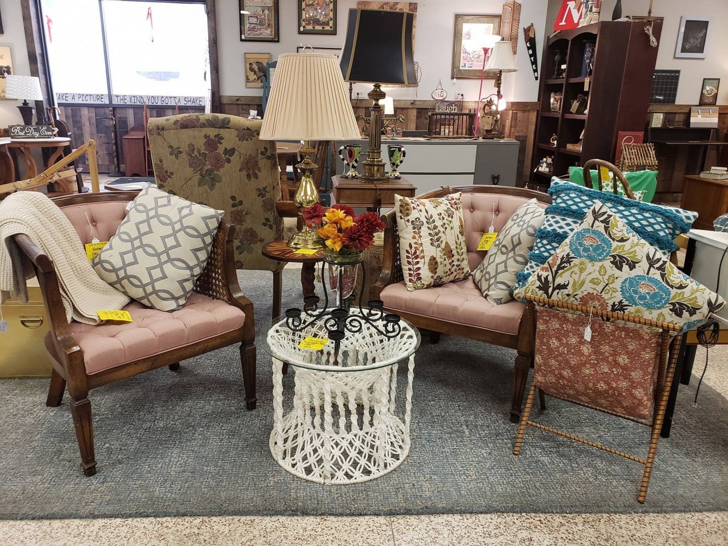 A living room with chairs, tables, lamps and pillows.