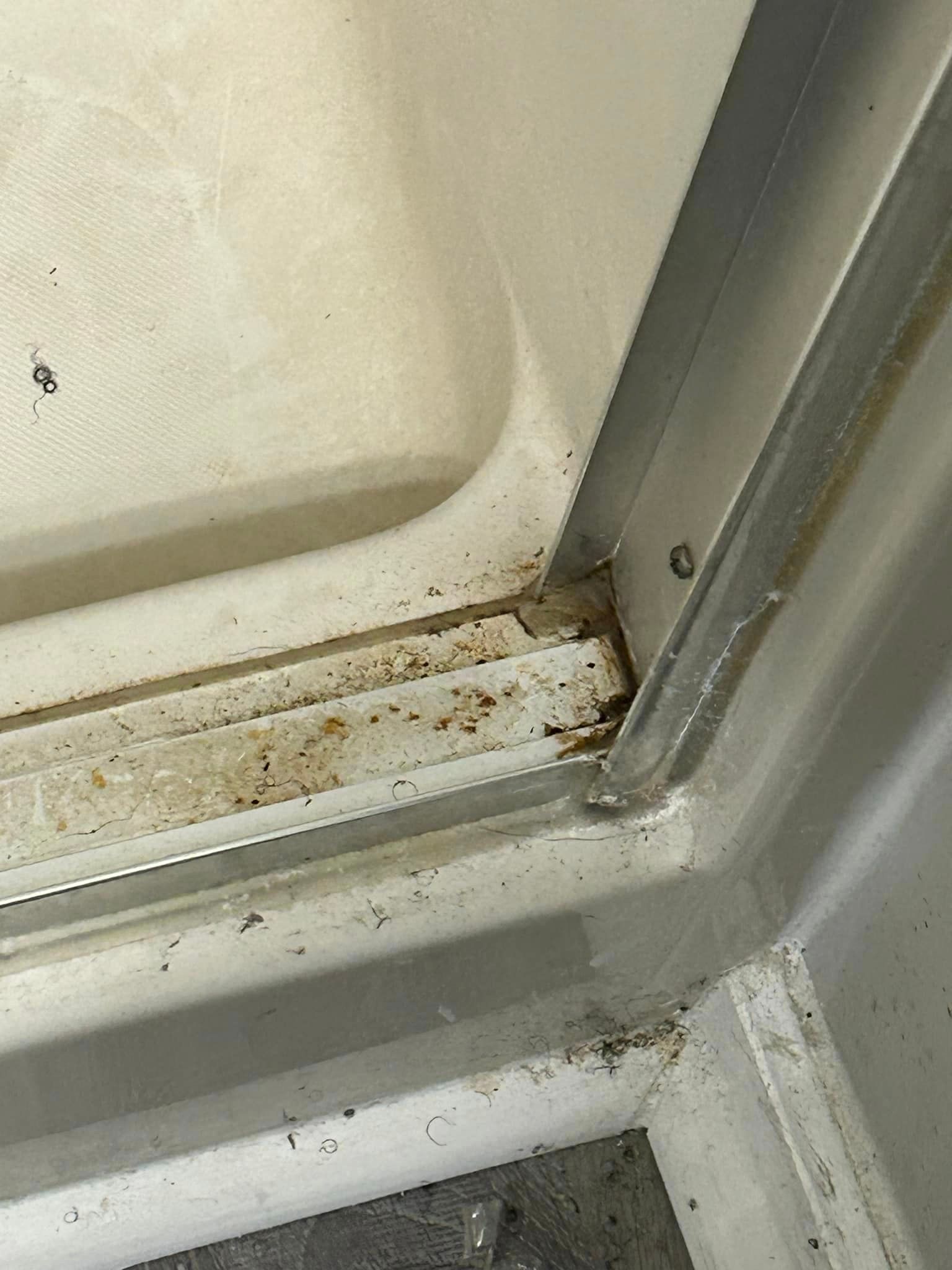 A close up of a dirty shower door with a sliding glass door.