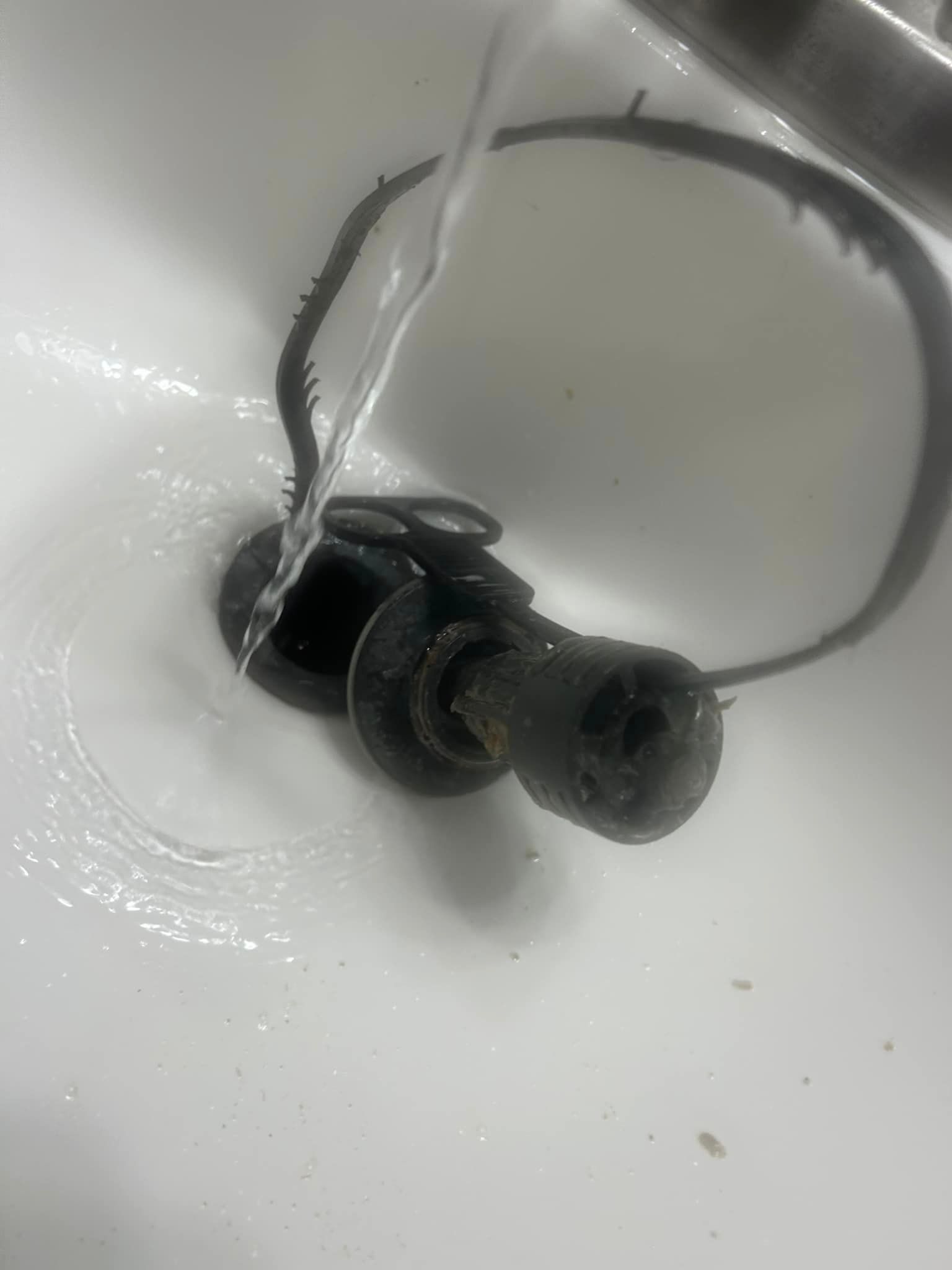 A pair of headphones are being washed in a sink.