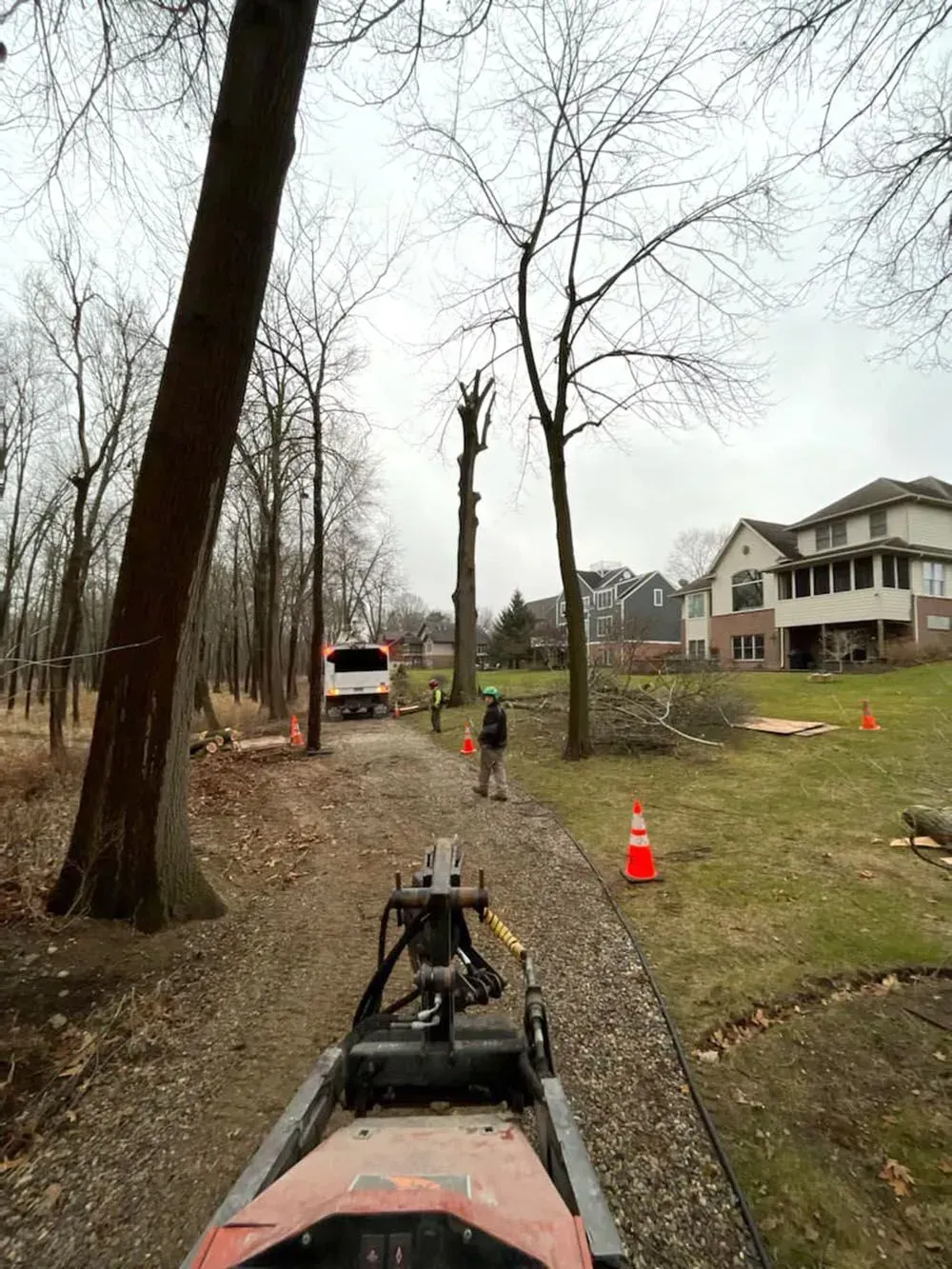 A person is riding a snowmobile down a dirt road next to a house.
