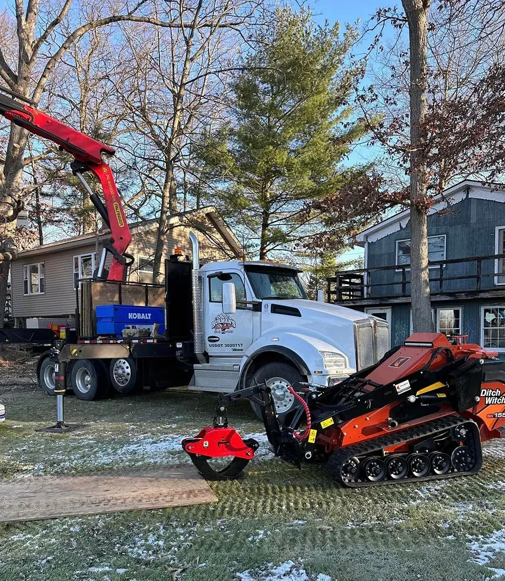 A truck with a crane attached to it is parked in front of a house.