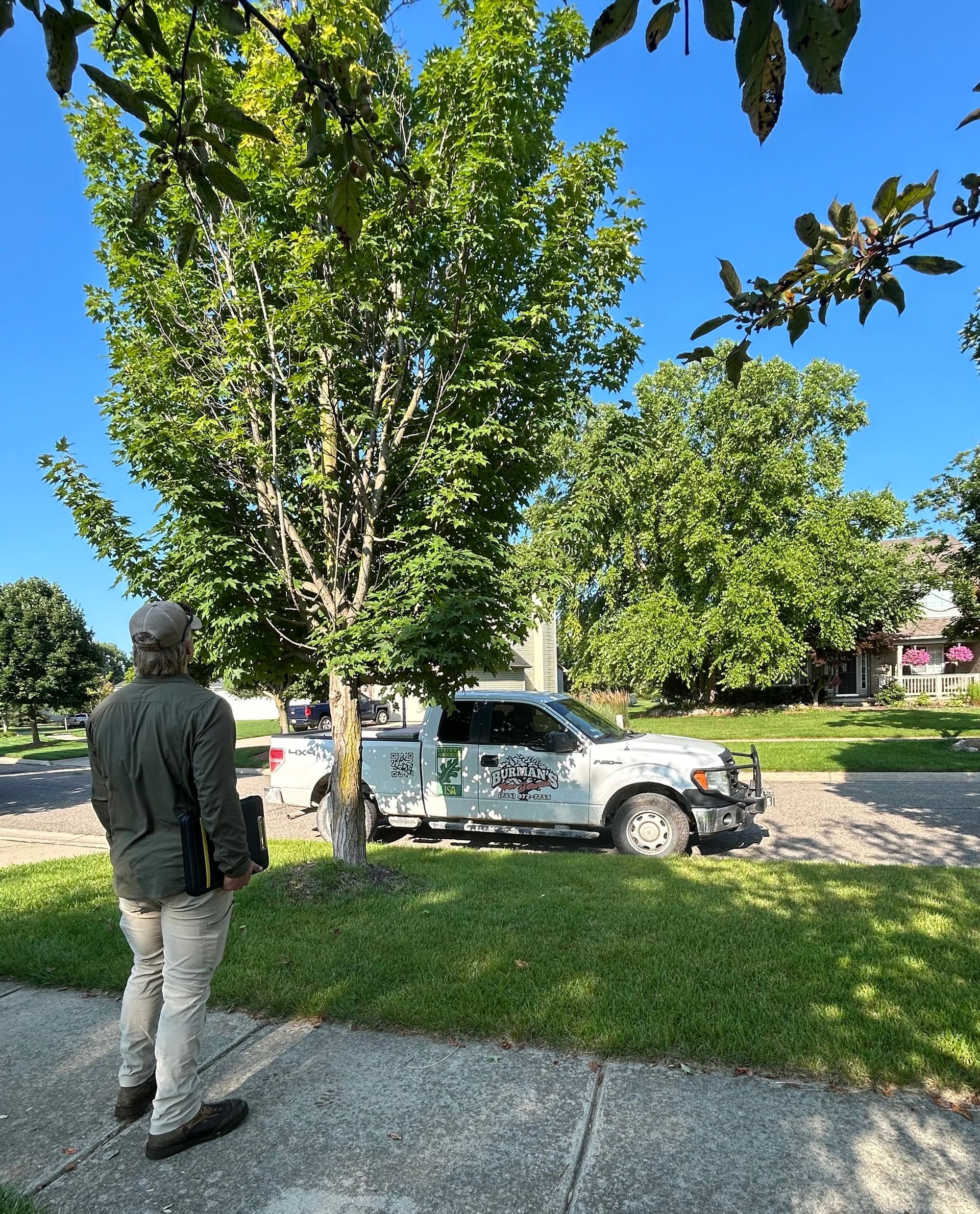 A man is standing on the sidewalk next to a white truck.