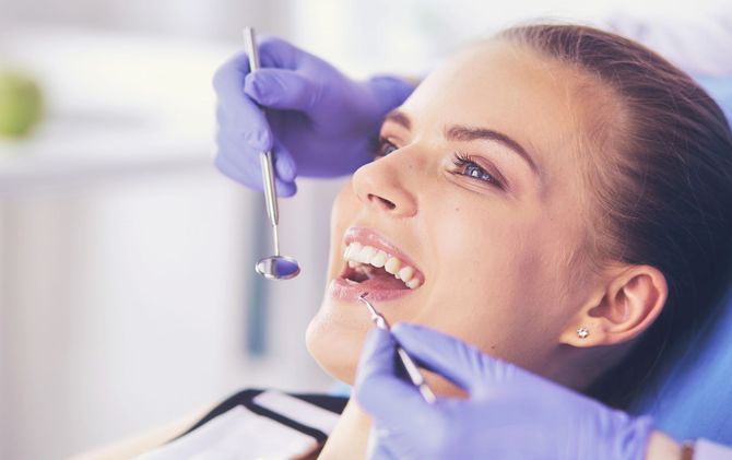 Dentista che usa uno strumento per esaminare i denti di un paziente sorridente in una clinica