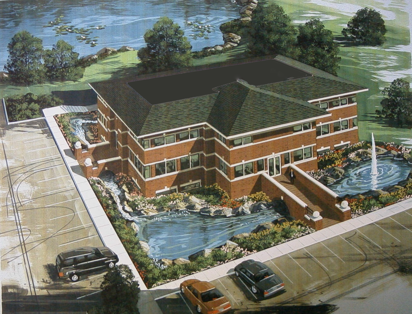 An aerial view of a large brick building with a fountain in front of it