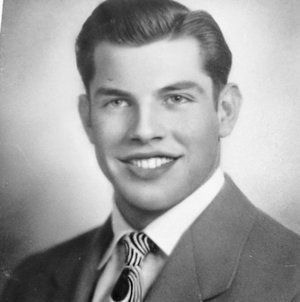 A man in a suit and tie is smiling in a black and white photo