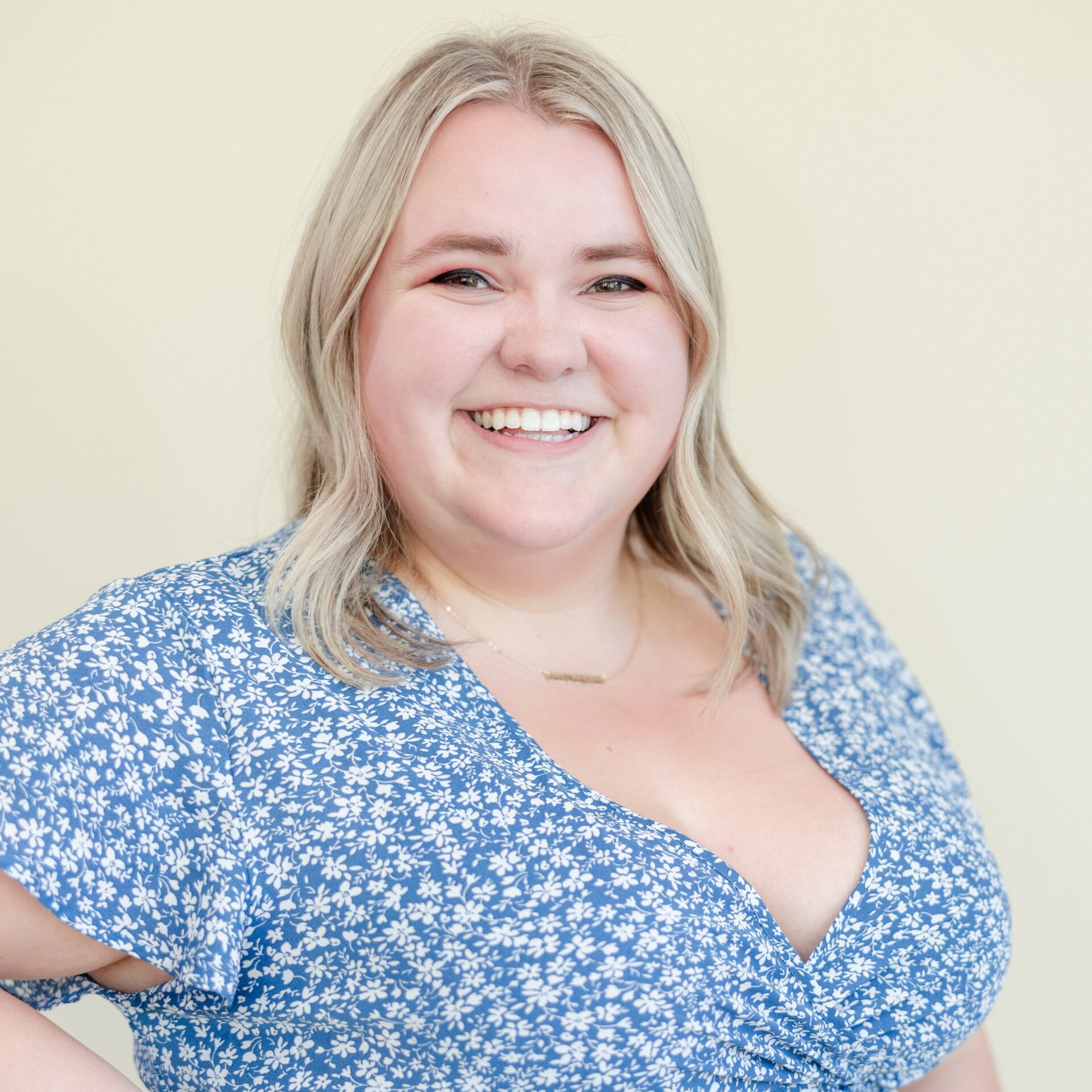A woman in a blue floral dress is smiling for the camera.