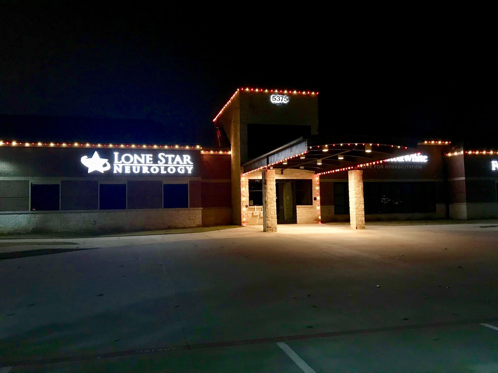 Night view of Lone Star Neurology clinic entrance with lit sign and covered driveway