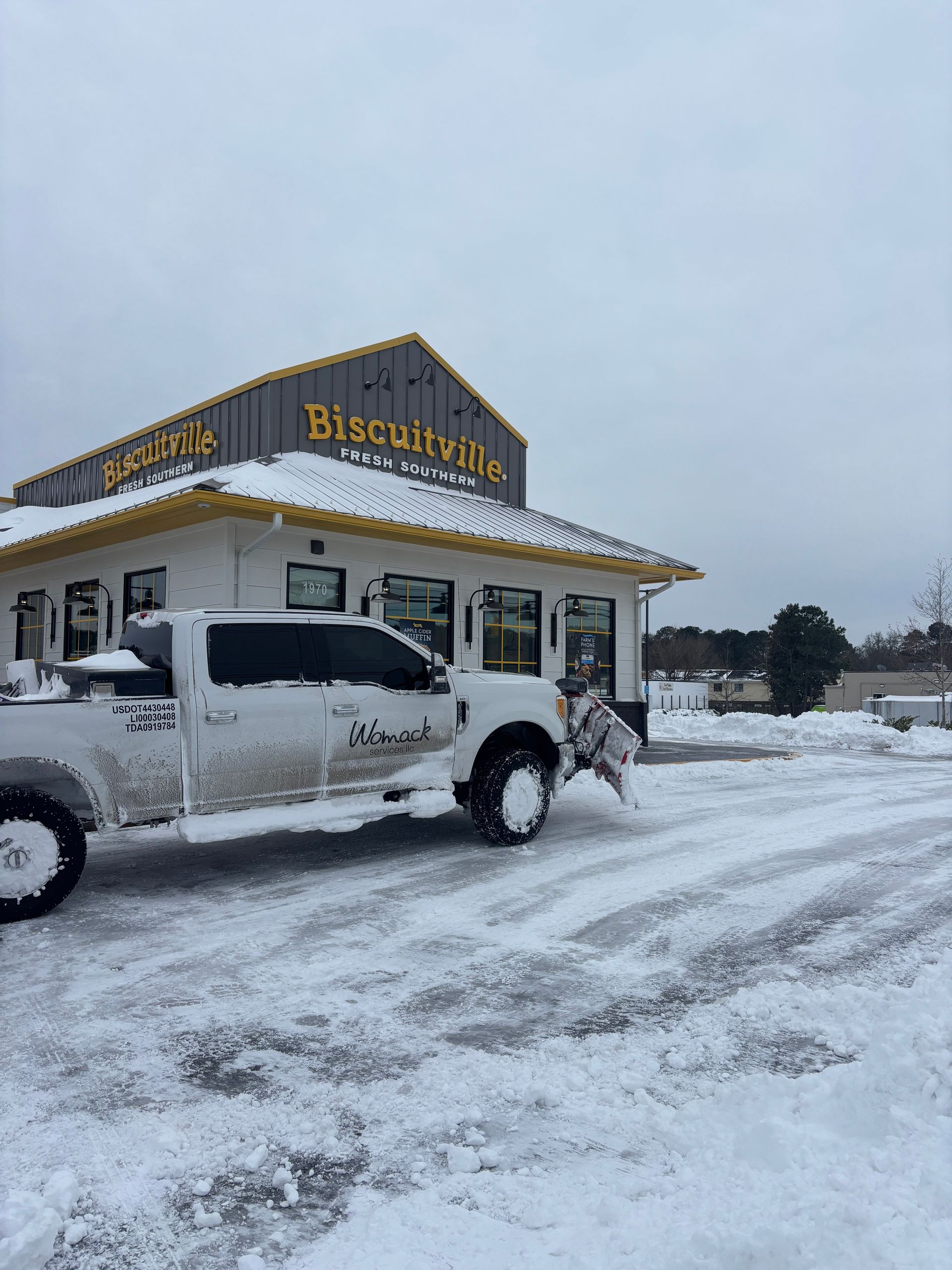 Snow-covered Biscuit Barn storefront with parked white pickup truck in a snowy lot
