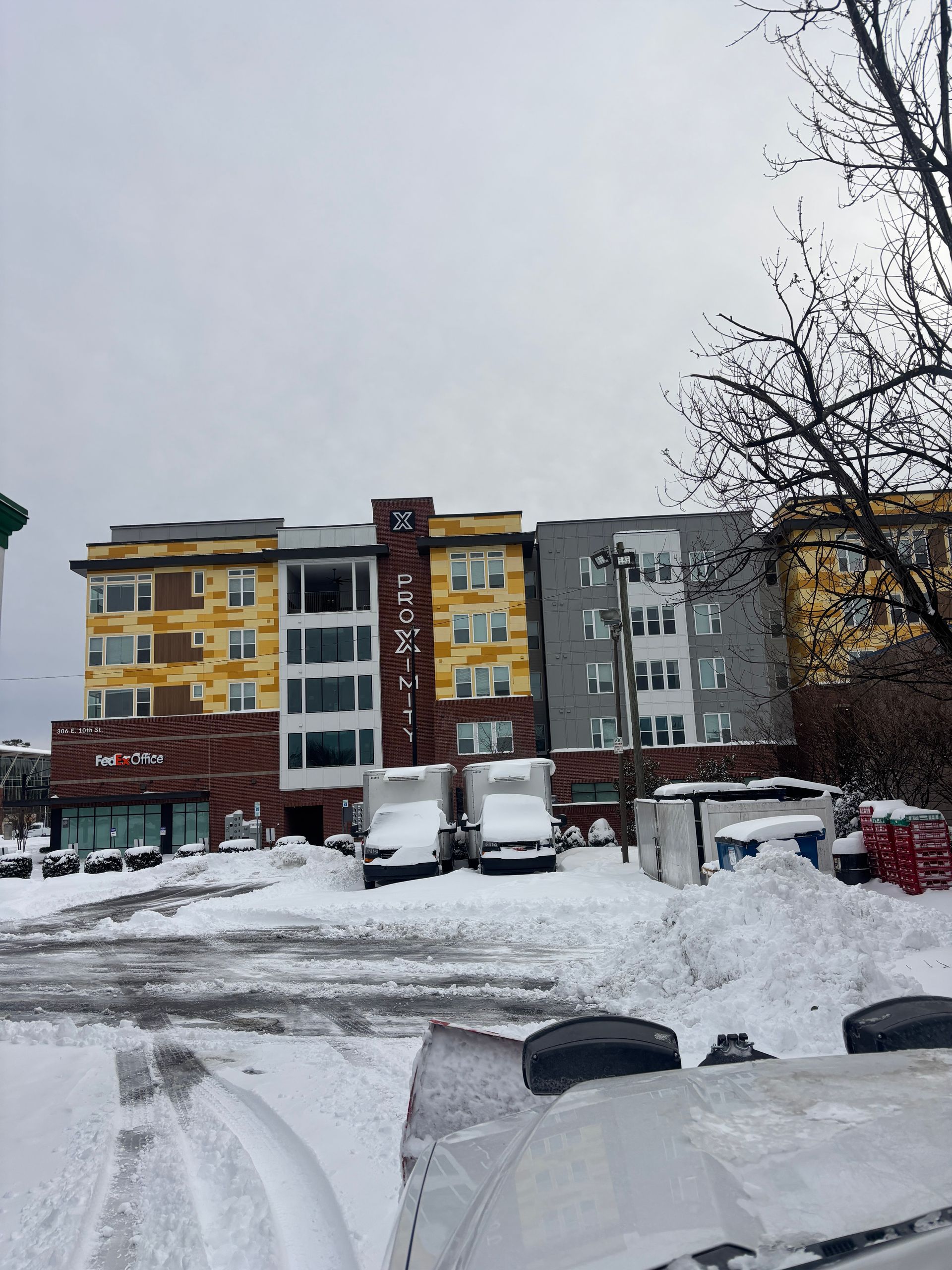 Snowy apartment buildings with parked vans in a winter residential area
