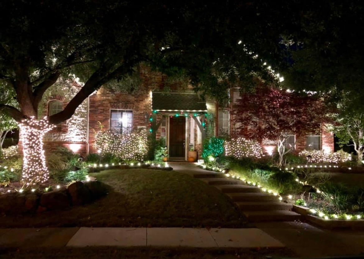 House with festive string lights illuminating the front yard at night