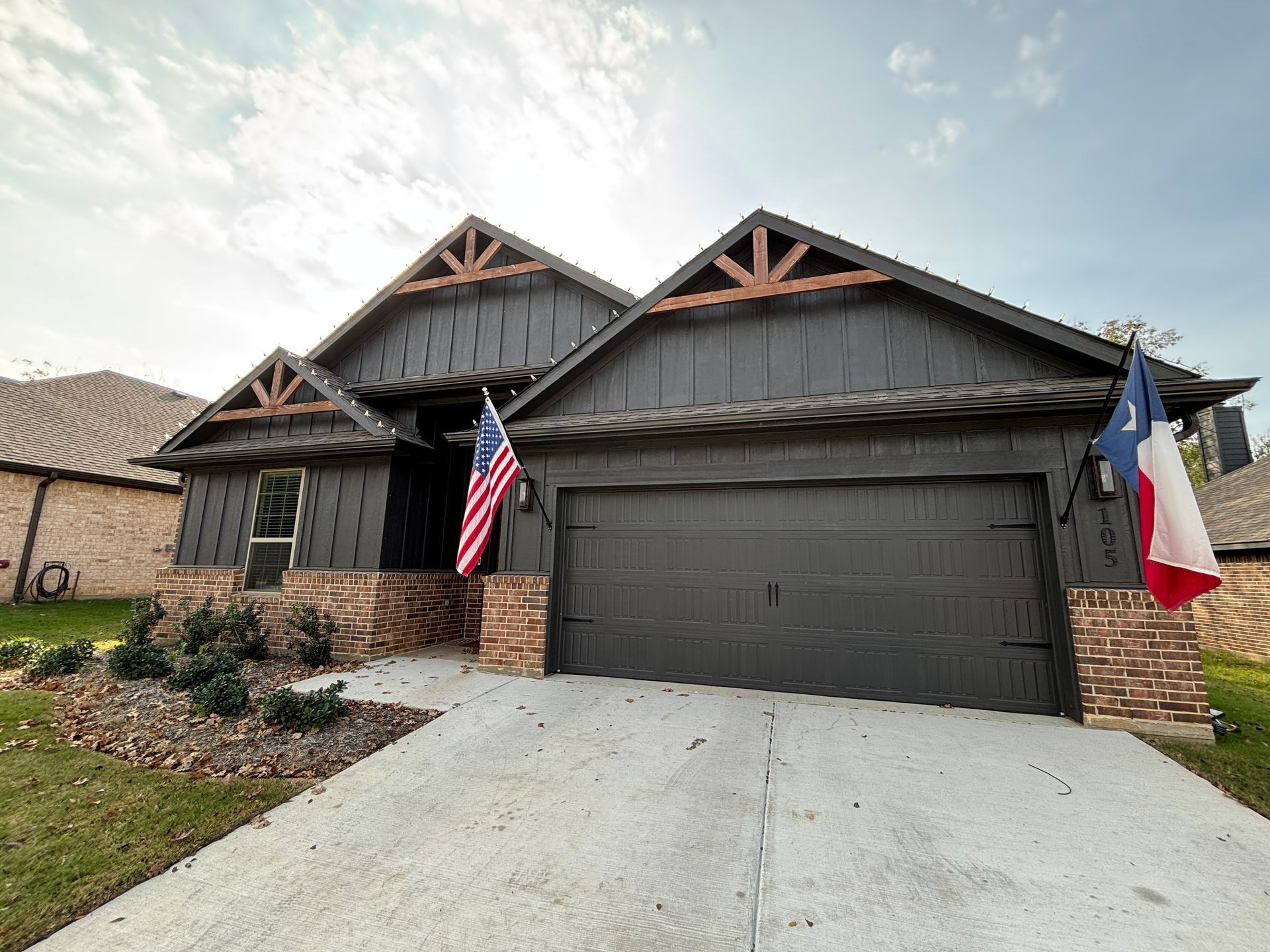 Suburban house with a two-car garage, American and Texas flags, and a concrete driveway