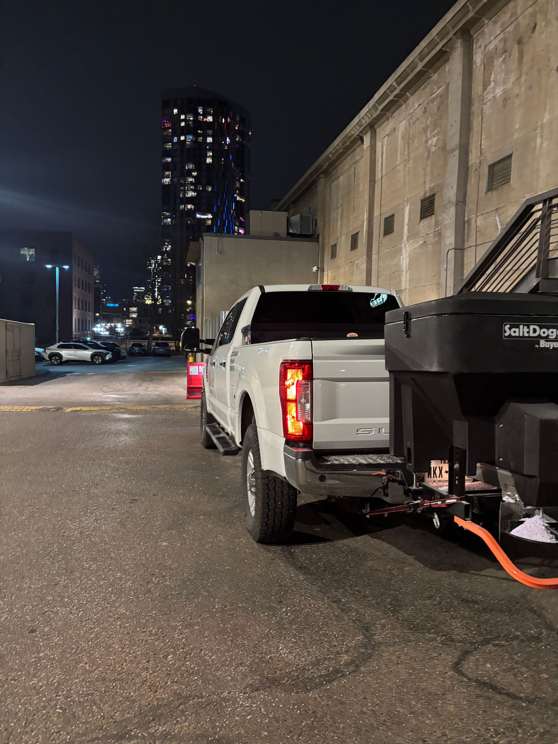 Pickup truck towing a black trailer on a snowy city street at night