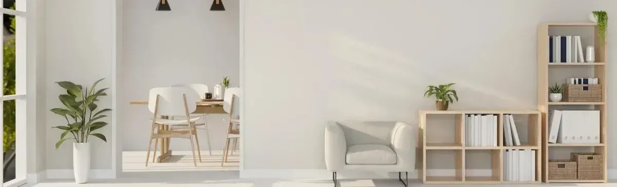 Minimalist white living room with a desk, armchair, plants, and bookshelf shelves