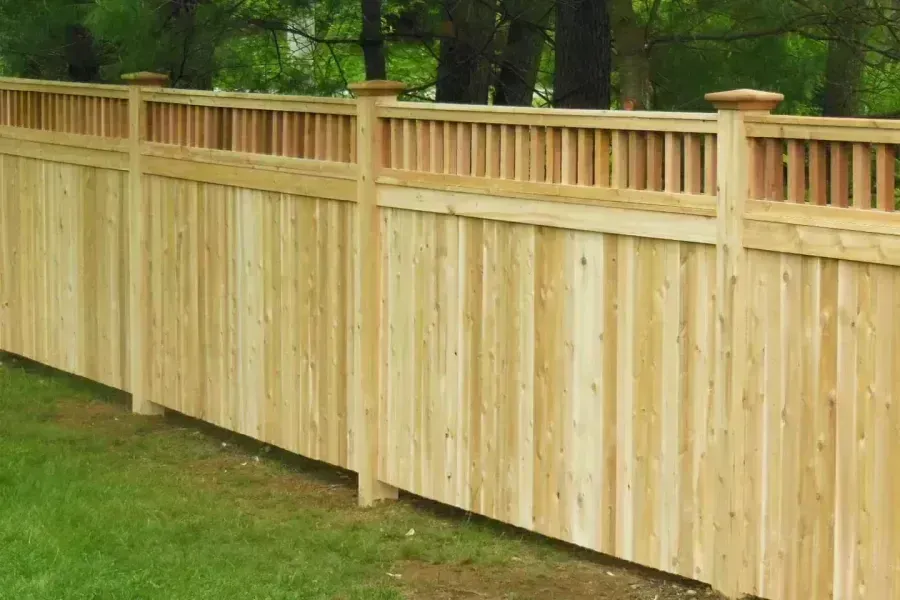 Wooden privacy fence along a grassy yard with trees in the background