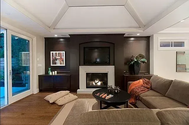 Modern living room with sectional sofa, fireplace, TV, sliding glass doors, and dark accent wall