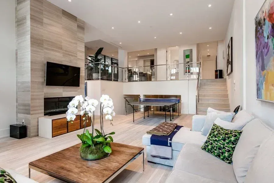 Modern open-plan living room with white sofas, fireplace, wall TV, and dining area