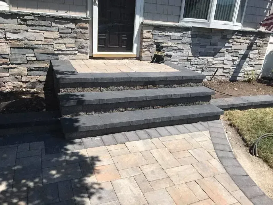Stone front steps and walkway leading to a house entrance with a black door and stone facade.