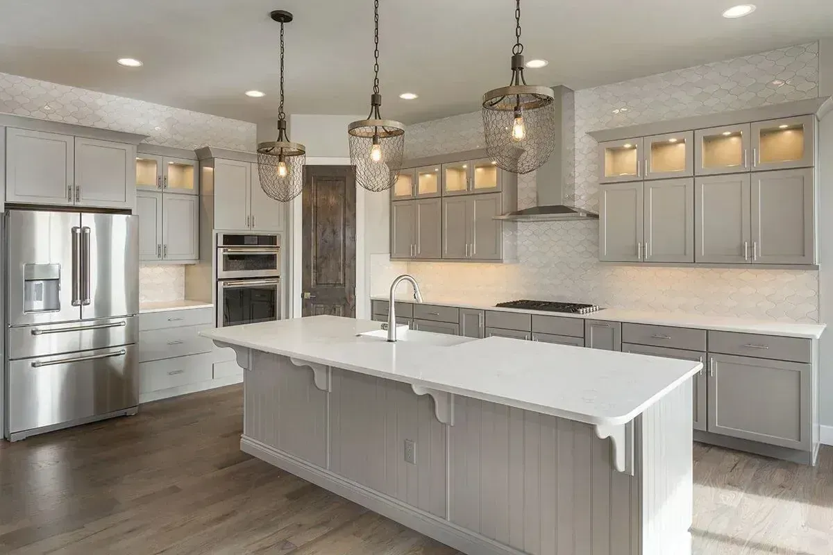Modern gray kitchen with white island, stainless steel appliances, and pendant lights