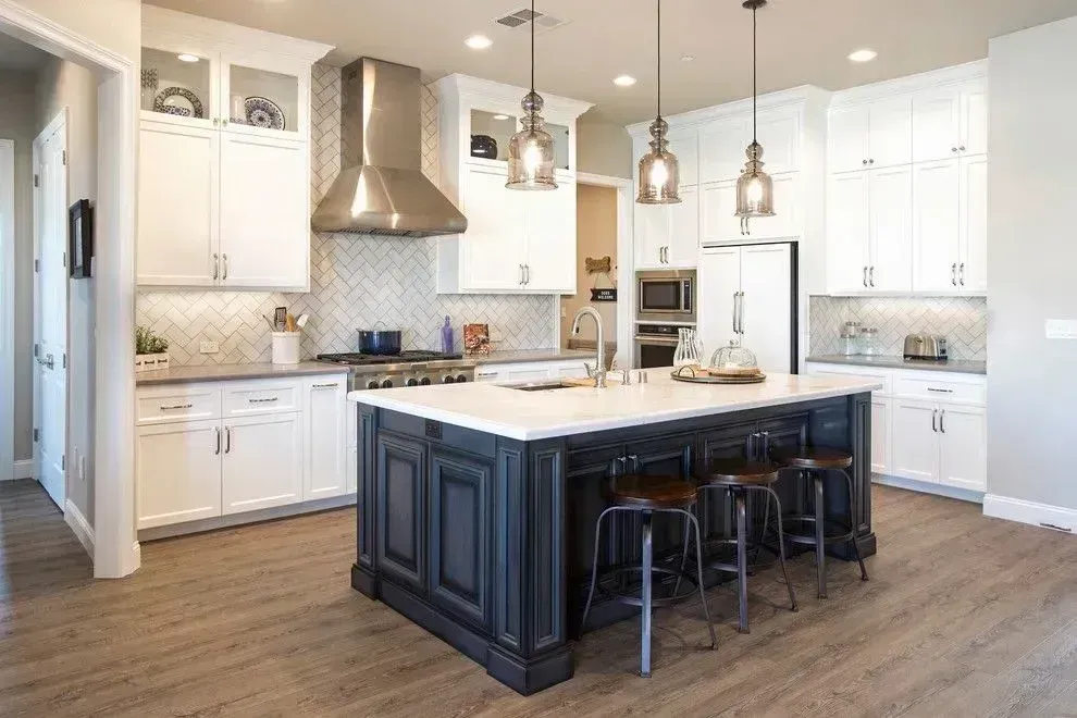 Bright modern kitchen with white cabinets, large island, pendant lights, and wood flooring
