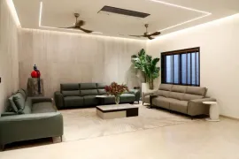 Modern living room with leather sofas, a coffee table, ceiling fans, indoor plant, and large window.