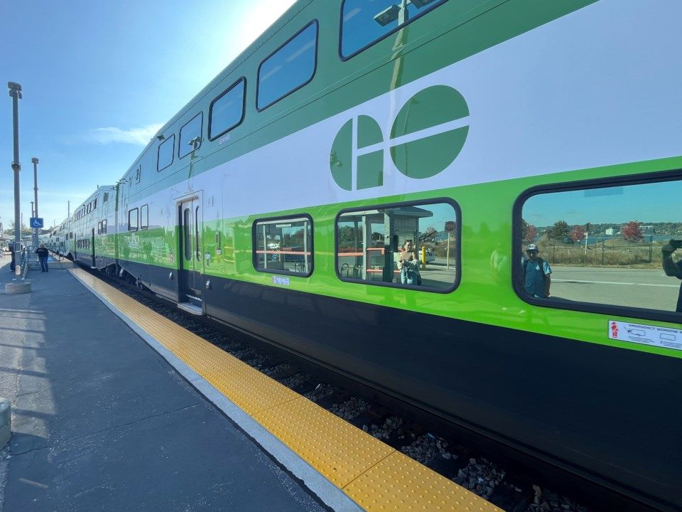 A green and white train is parked at a train station.
