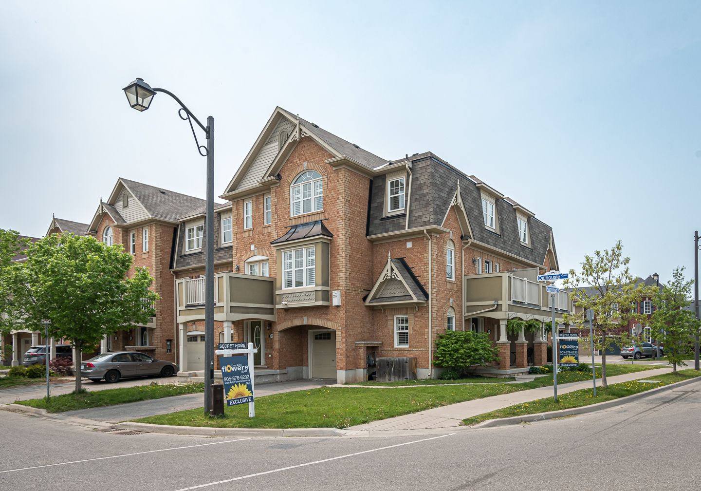 A large brick house with a for sale sign in front of it.