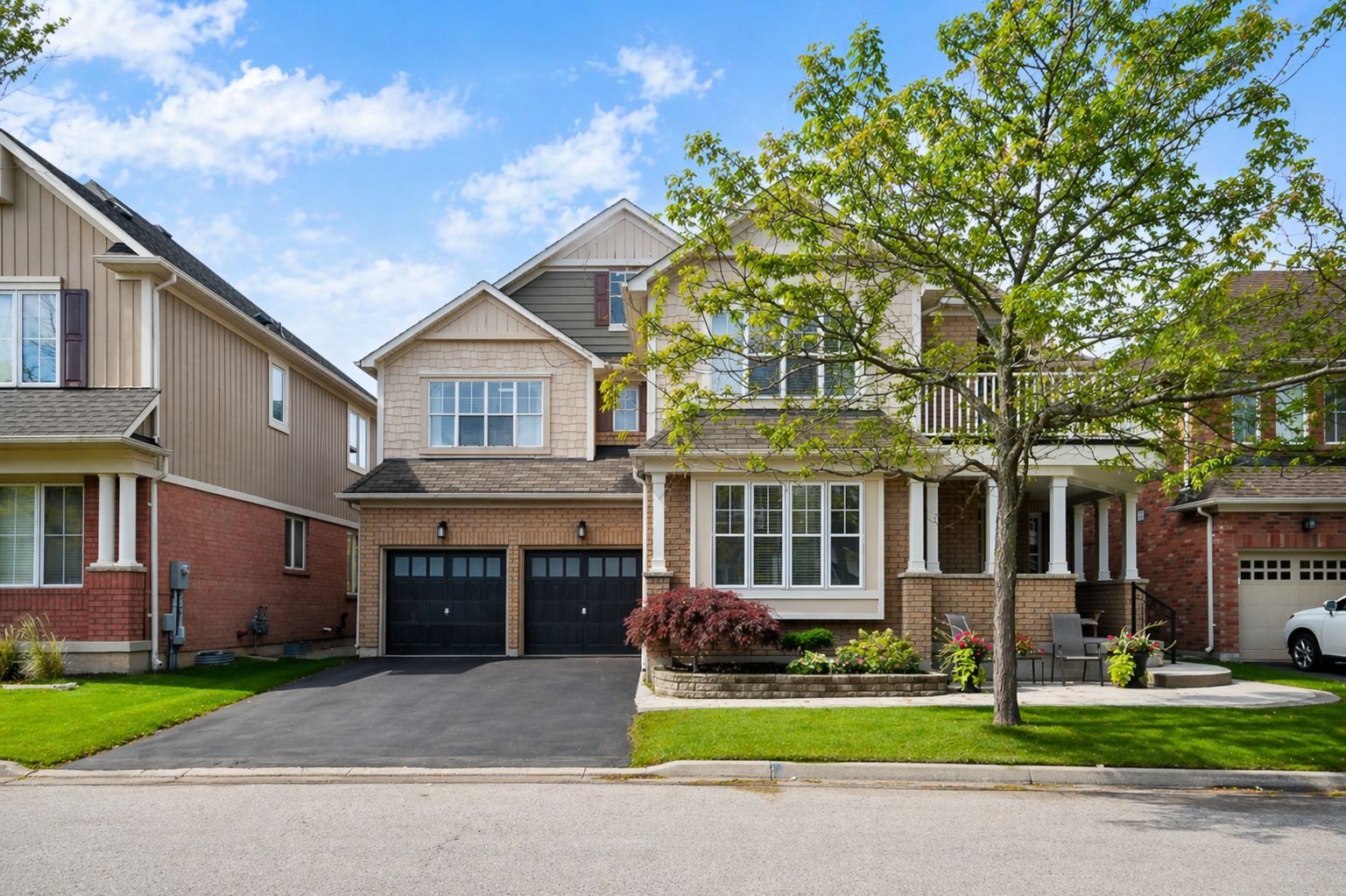 Suburban two-story house with a double garage, front porch, and a tree in the yard