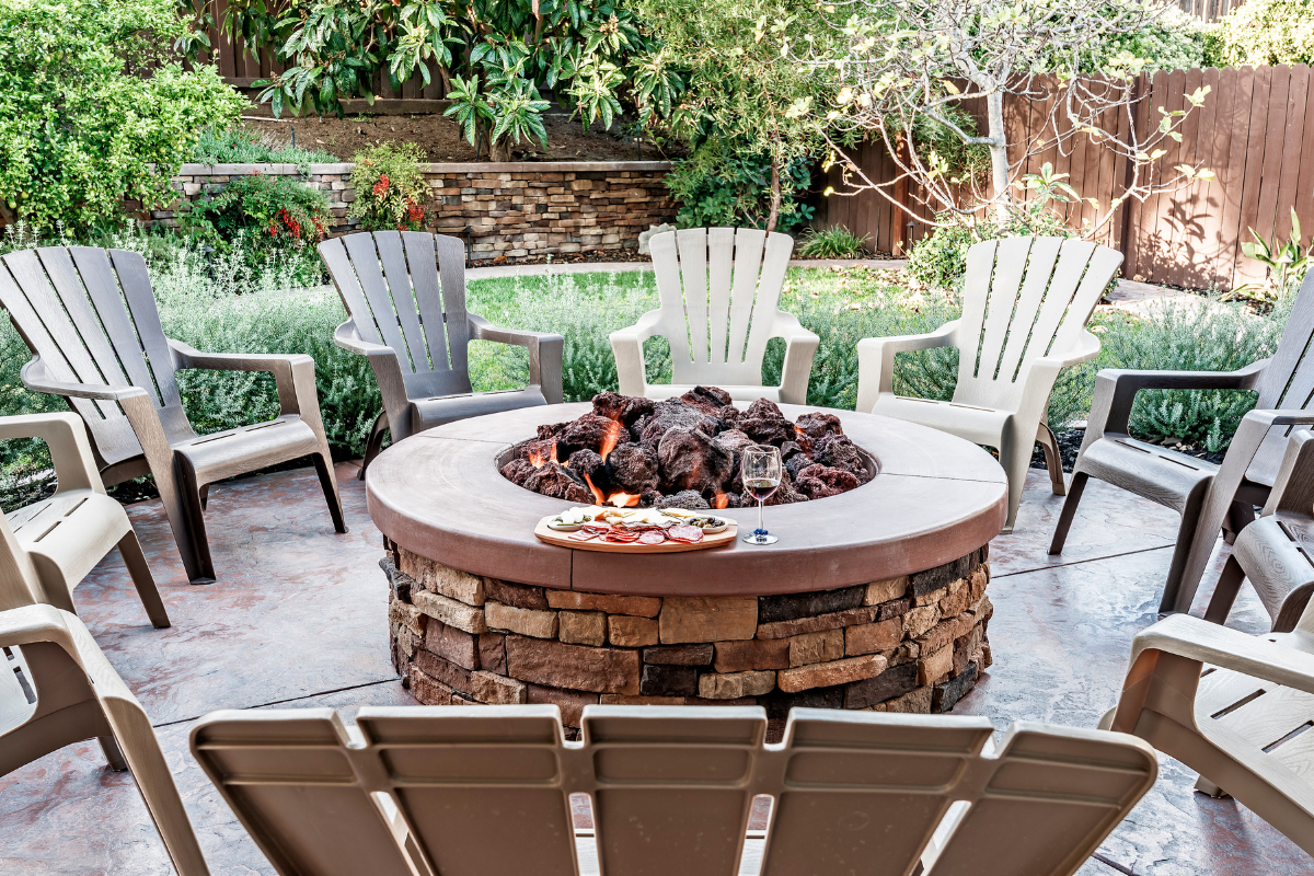 A fire pit is surrounded by chairs on a patio.
