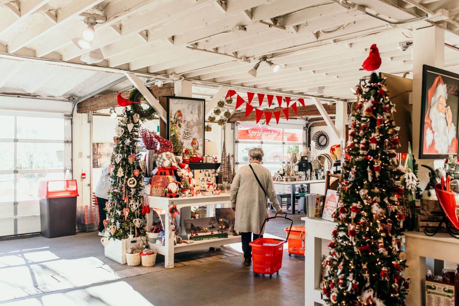 A woman is walking through a store filled with christmas decorations.
