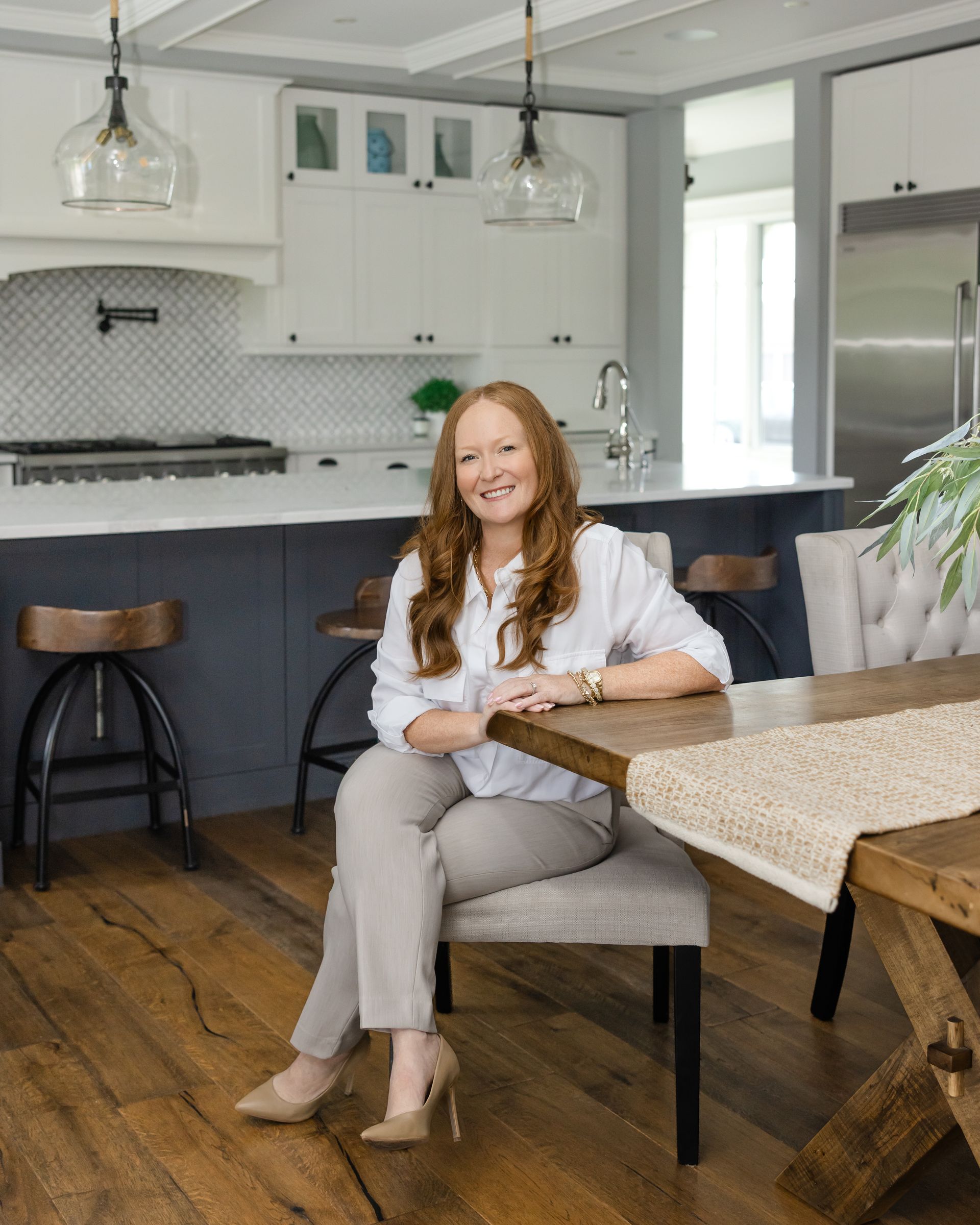 Woman in green blazer smiles, holding paperwork in doorway.