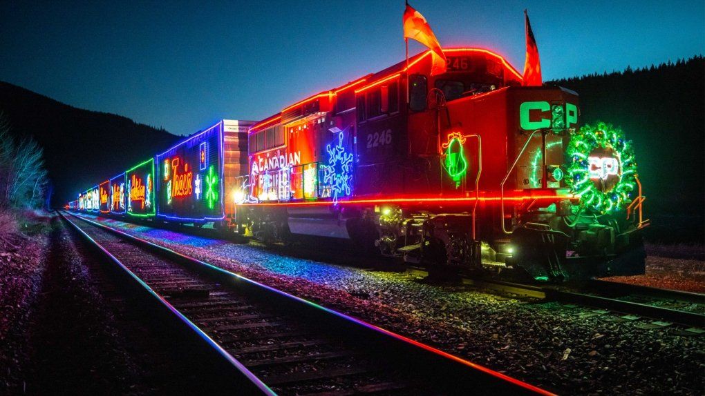 A train is decorated with christmas lights and is on the tracks.