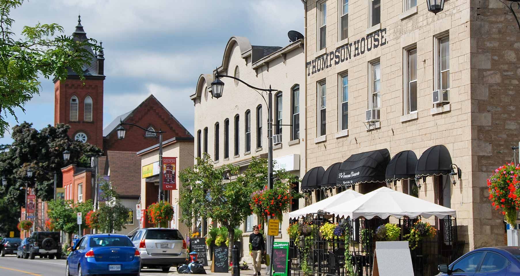 Street view of historic buildings with shops, a clock tower, and outdoor dining.