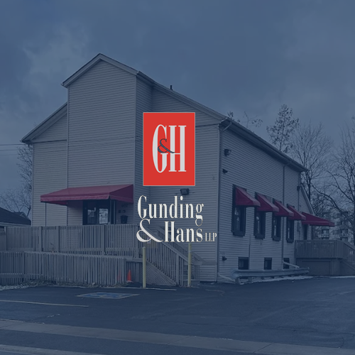 A gray two-story building with red awnings, overlaid with a logo for the law firm Gunding & Hans LLP.
