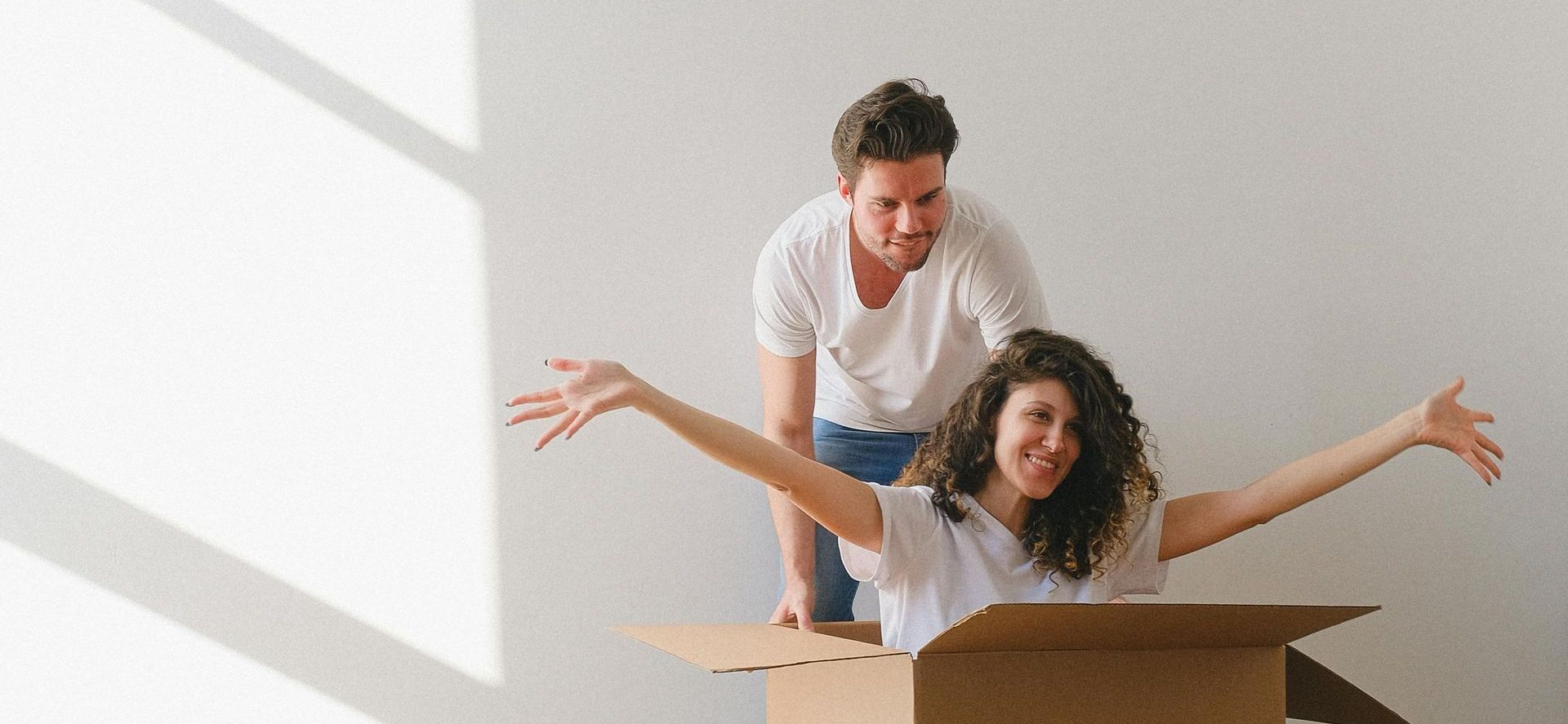 A man and a woman are playing with a cardboard box.