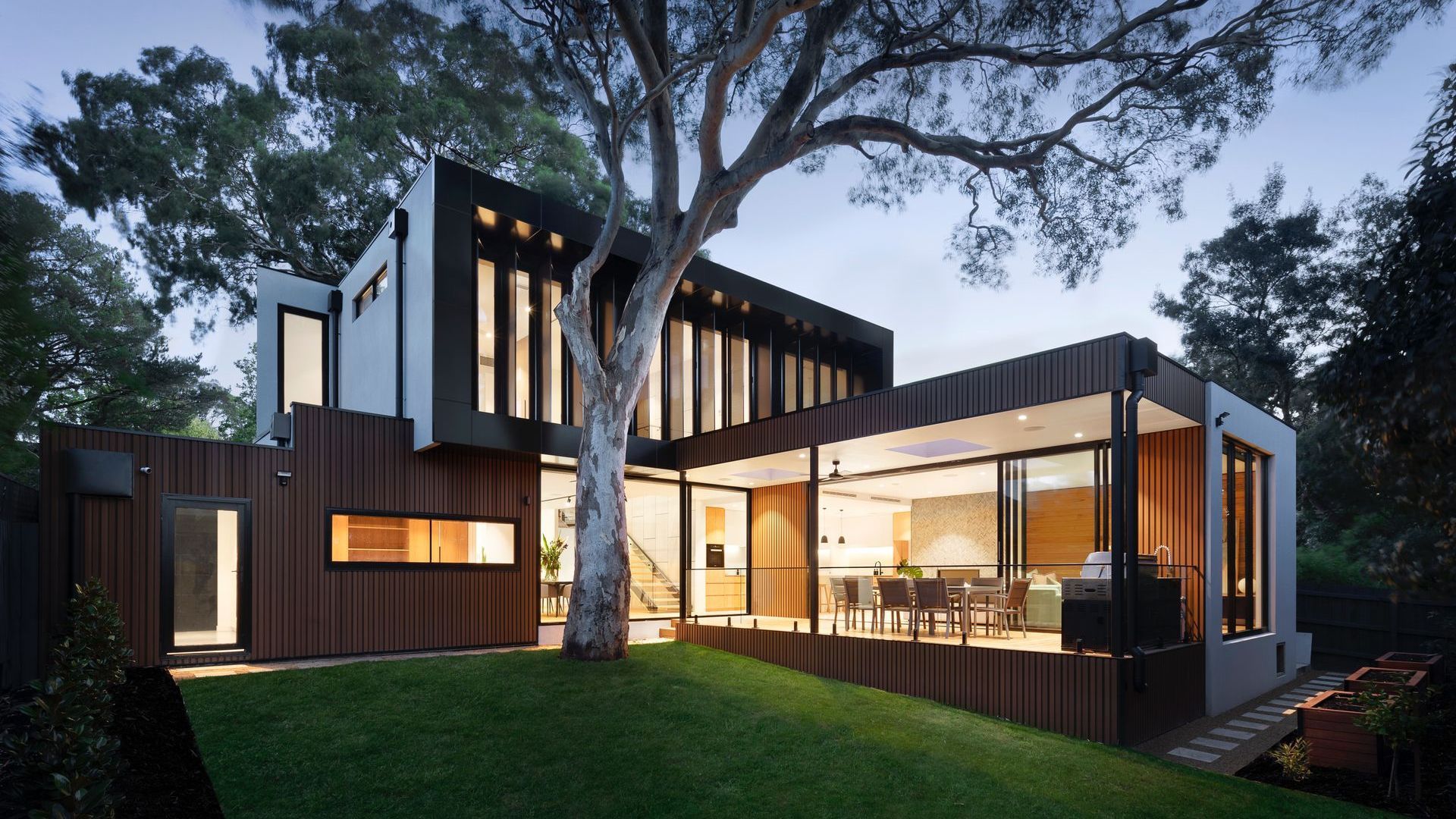 A modern house with a lot of windows and a tree in front of it