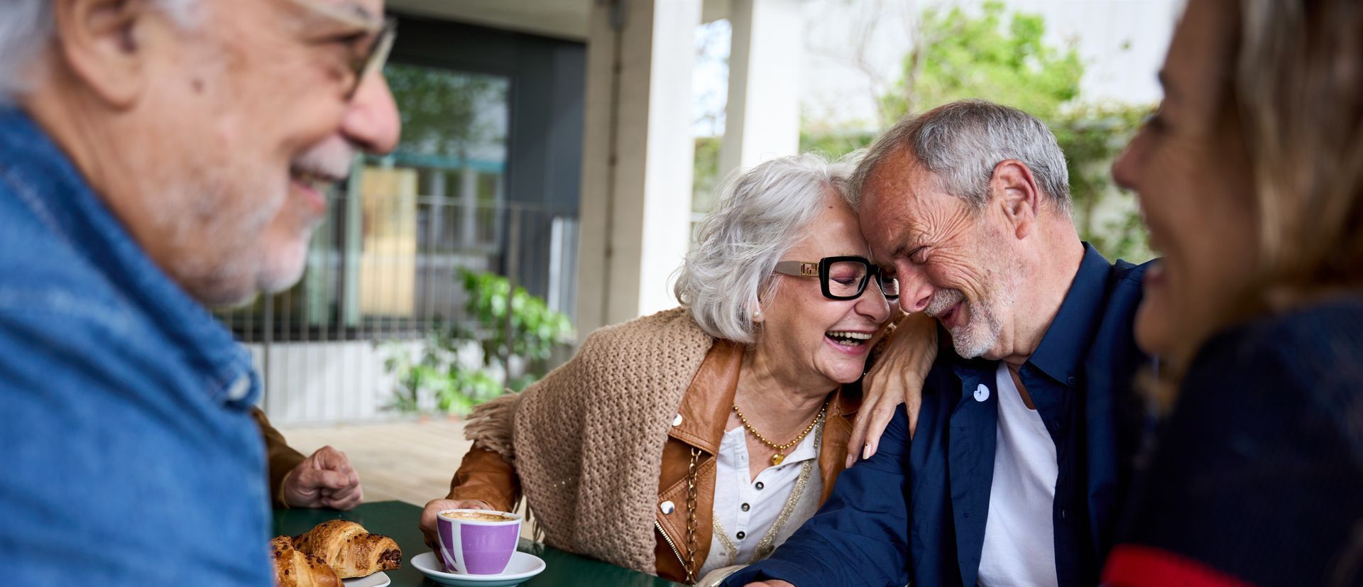 A group of elderly people are sitting at a table talking to each other.